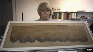 Conservationist holds up fragment of the Dead Sea Scrolls.