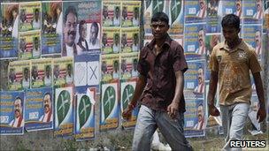 Two men walk past local government election campaign posters in Jaffna, Sri Lanka, on Friday