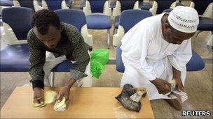 People count the old currency before receiving the new Sudanese currency at a branch of the central bank of Sudan in Khartoum
