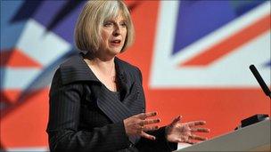 Theresa May speaking with a union flag behind her