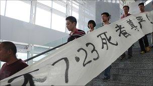 Protesters carrying a banner saying 'return dignity to the victims who died on July 23' demonstrate in the hope of learning the truth of the July 23 high-speed train collision, at a railway station in Wenzhou, in eastern China's Zhejiang province on July 27,