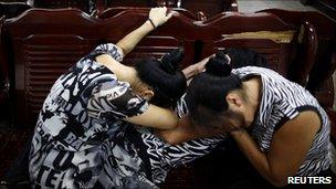 Women cry at a mortuary where people had gathered to search for their missing relatives