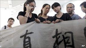 A woman weeps as she and others hold a banner demanding the truth for the train crash in east China"s Zhejiang province, 27 July 2011