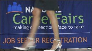 A woman walking past a career fair sign