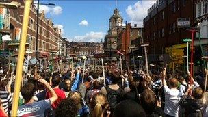 Clean-up volunteers wave brooms at Clapham Junction