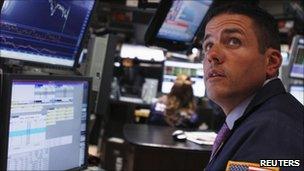 A trader works on the floor of the New York Stock Exchange as he listens to an announcement by the Fed in New York August