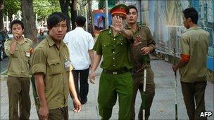 A policeman tries to stop a foreign journalist taking pictures as they guard the Ho Chi Minh City People's Court