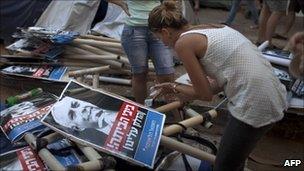 Demonstrator leaning over pile of banners showing Mr Netanya face