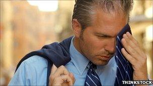 Man wipes away sweat with his tie