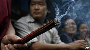 A monk holds incense in Dharmsala, India, Wednesday, 20 July 2011