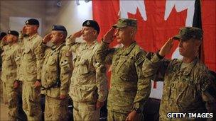 Canadian and American troops salute in Afghanistan