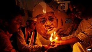 Supporters of Indian anti-corruption activist Anna Hazare hold a candlelight vigil in front of his picture in Allahabad on 16 August 2011