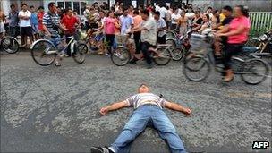 A man lies in front of one of the closed schools in protest on 16 August 2011