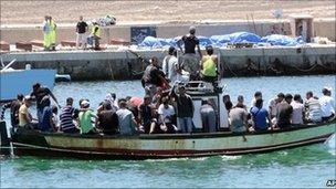 Migrants on a boat sailing past the Lampedusa port