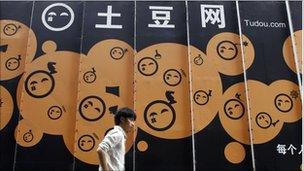 A pedestrian walks by Tudou's headquarters in Shanghai