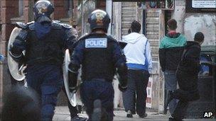 Riot police chase youths during civil disturbances in Manchester