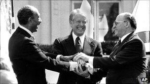 Egyptian President Anwar Sadat (left) with US President Jimmy Carter (centre) and Israeli PM Menachem Begin clasp hands after signing the peace treaty on 26 March 1979 at the White House