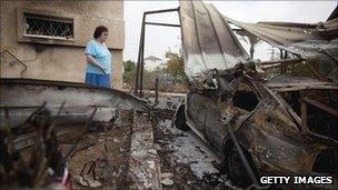An Israeli woman in Beersheba looks at a car that was hit by a rocket fired by Palestinian militants from the Gaza Strip on Saturday
