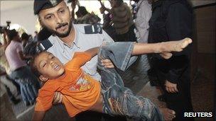 A policeman carries a wounded boy into a hospital following an Israeli air strike in Gaza City on 20 August 2011