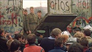 West Berliners crowd in front of the Berlin Wall early 11 November 1989 as they watch East German border guards demolishing a section of the wall in order to open a new crossing