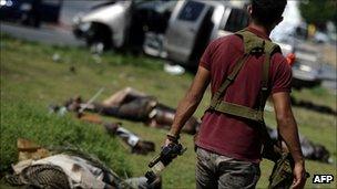 A rebel soldier walks past dead pro-Gaddafi soldiers in Tripoli, Libya (25 Aug 2011)