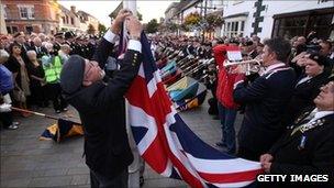 A standard bearer lowers the union jack in Wootton Bassett