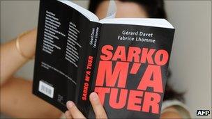 A woman poses in Paris with the book "Sarko m'a tuer" (Sarkozy Has Killed Me), 31 August