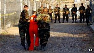 Army guards escorting a prisoner at Guantanamo Prison