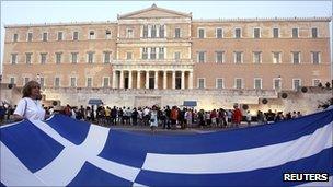 A protester holds a giant Greek national flag in front of the parliament building during a rally against austerity economic measures and corruption in Athens' Syntagma (Constitution) square on 3 September 2011