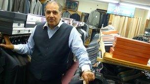 Moshe Rouach in his shop, with a picture of the twin towers behind him.