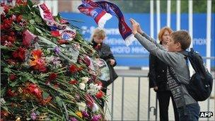 A fan throws a Lokomotiv Yaroslavl scarf onto a pile of flowers