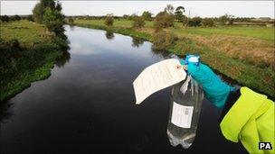 An Environment Agency worker holds a sample bottle of water from the River Trent in Staffordshire