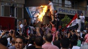 Protesters wave the Egyptian flag and set fire to a depiction of an Israeli one outside the Israeli embassy in Cairo.