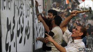 Protesters used hammers to tear down the concrete wall erected around the embassy.