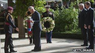 The Prince of Wales laying a wreaths at the memorial, watched by David Cameron (r) and Louis Susman