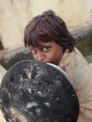 A child waits to fill his water jar from a communal tap