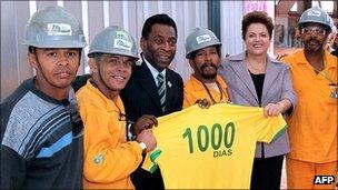 Brazilian President Dilma Rousseff and Pele with construction workers holding a Brazil shirt with 1000 days written on the back.