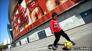 A youngster plays football outside Arsenal's Emirates Stadium