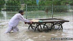 A man wades through a flooded street in Sindh