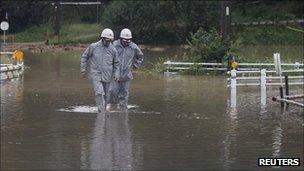Firemen walk through floods in Toyota, Japan, on 21 September 2011