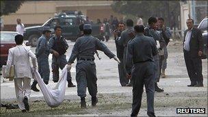 Afghan policemen carry the body of a suicide attacker in Kabul (13 Sept 2011)