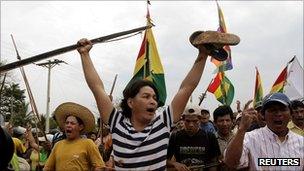 Indigenous protesters brandish bows and wave flags as they continue their march