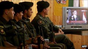 Palestinian security forces listen to President Obama on TV as he talks at Cairo University on 4 June 2009