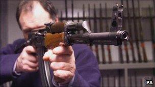 A man poses with a Kalashnikov rifle seized in Northern Ireland, 1999