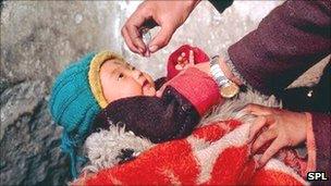 A doctor giving the polio vaccine to a child in India