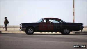 A 1958 Dodge car for sale is driven on Havana's seafront boulevard