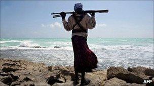 Armed man on coast of Somalia with MV Filitsa, seized by pirates, in distance - 26 January 2010