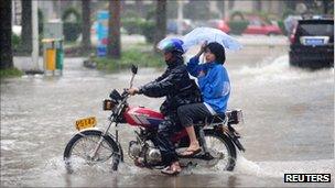 A man struggles to ride a motorbike during heavy rain brought by Typhoon Nesat in Qionghai, Hainan province on 29 Sept