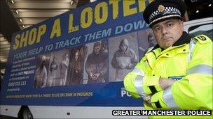 Policeman stood by a 'Shop a Looter' billboard