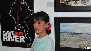 Burma democracy leader Aung San Suu Kyi poses next to campaign pictures opposing the construction of the Chinese-backed Myitsone dam, in Rangoon on 22 September 2011